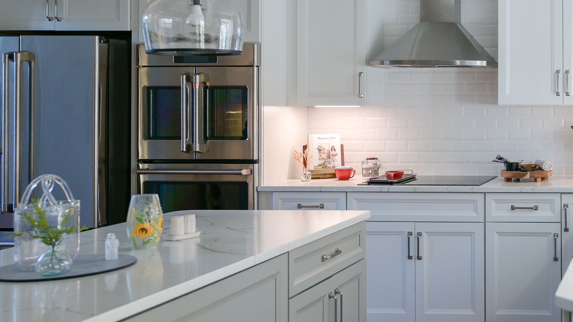 Modern white kitchen with stainless steel appliances, white cabinets, and island countertop.