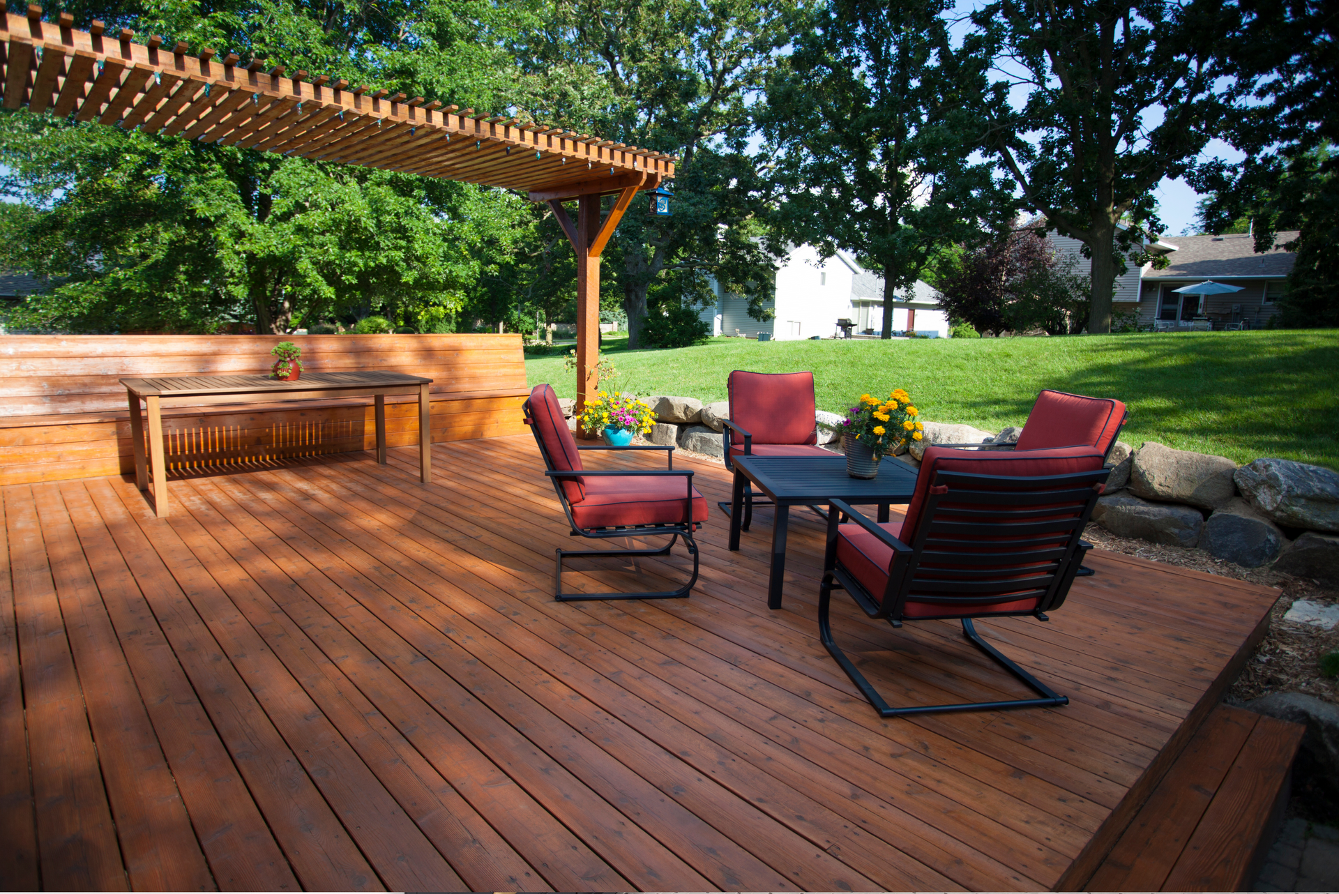 Patio with wicker chairs, a table, and a closed umbrella. A heater and a house are in the background.