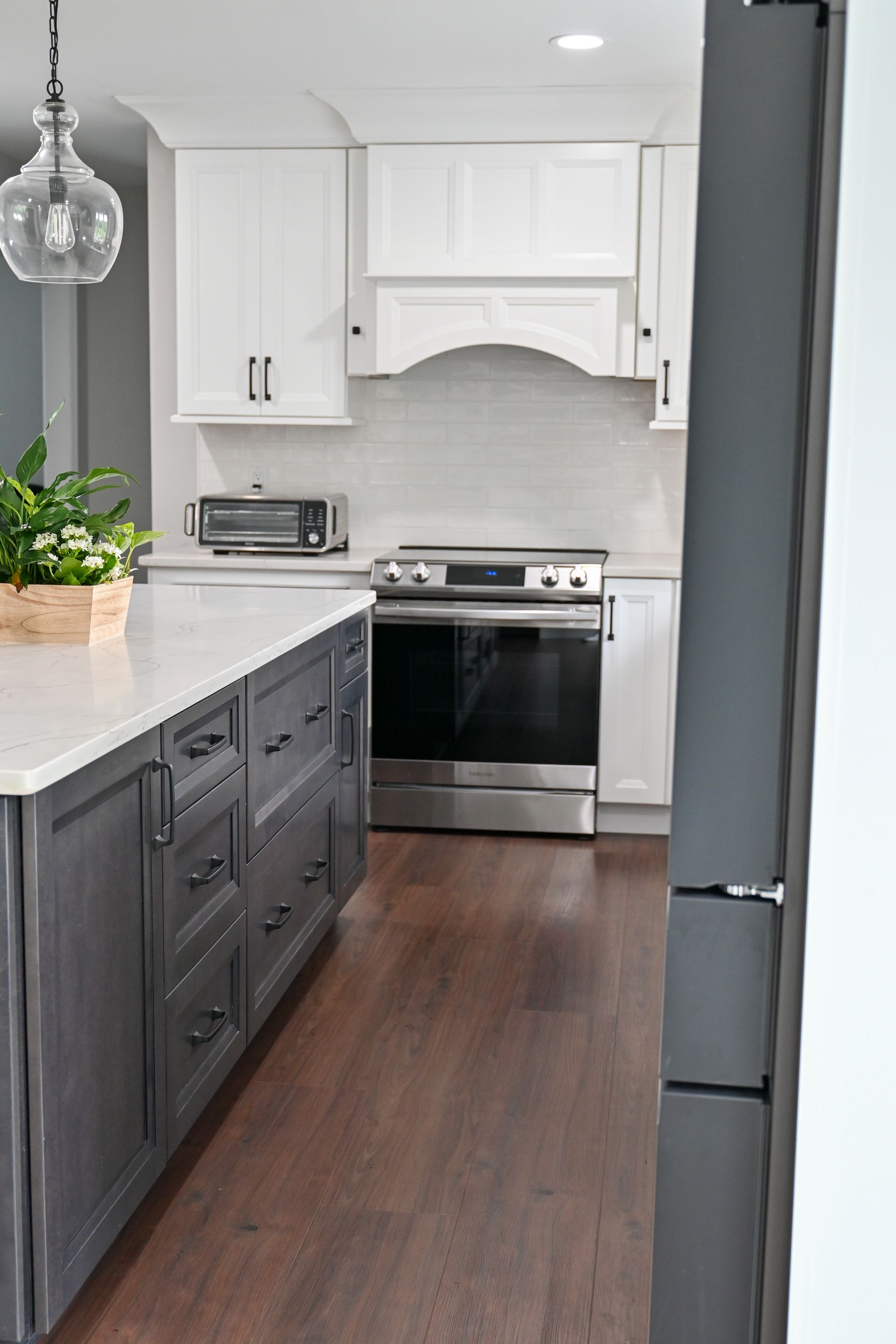 A kitchen with gray cabinets , white cabinets , stainless steel appliances , a stove and a refrigerator