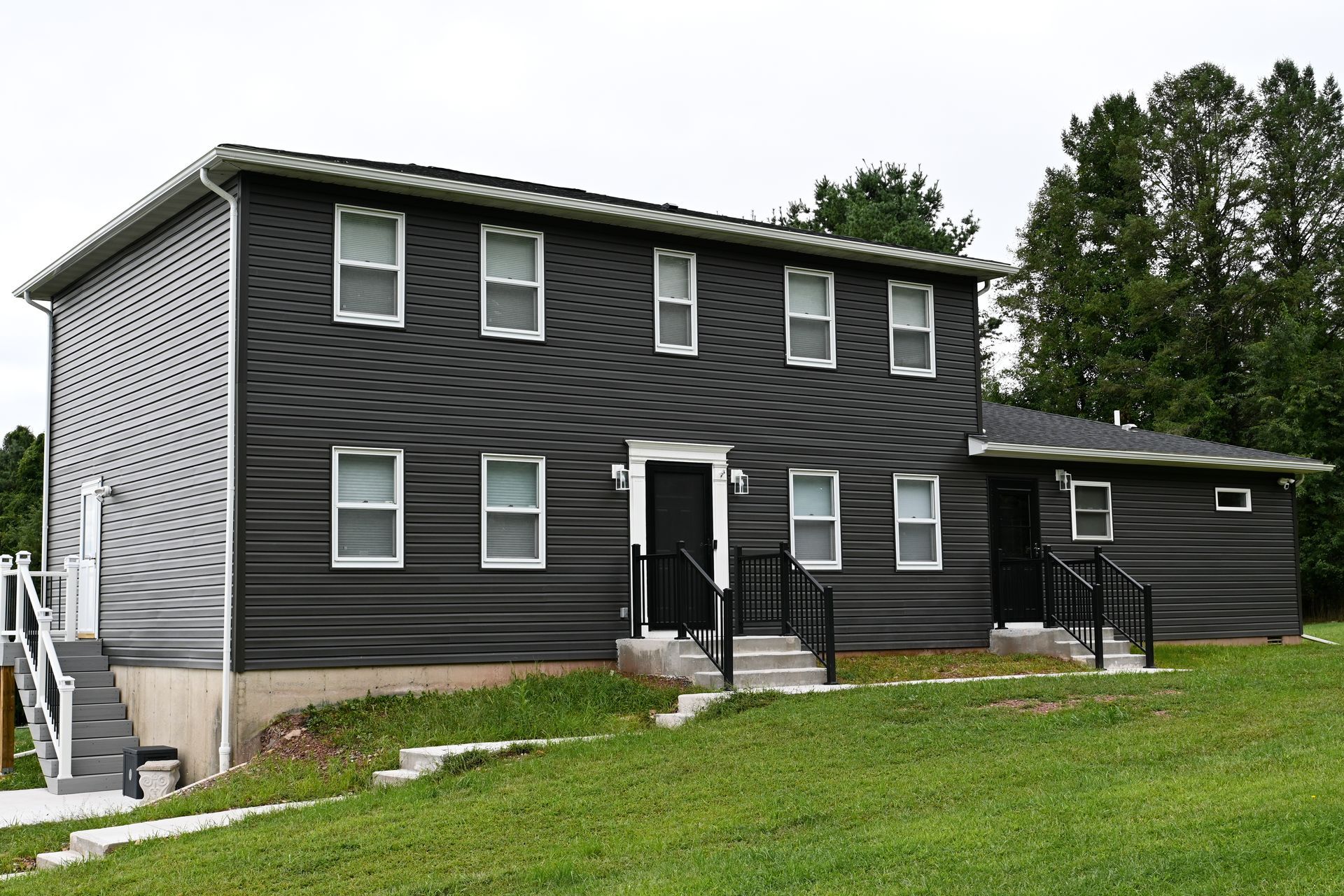 A black and white house is sitting on top of a grassy hill.