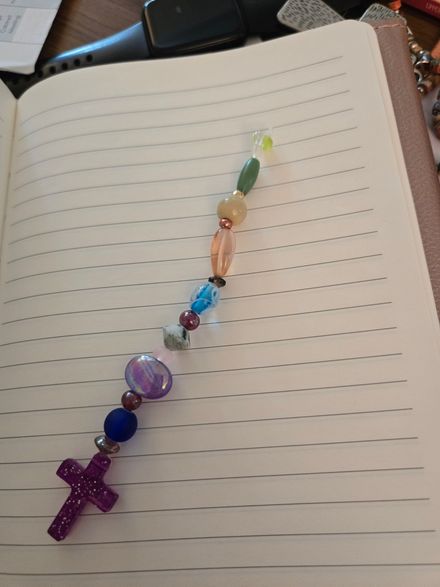 Colorful beaded rosary laid diagonally across an open lined notebook on a desk