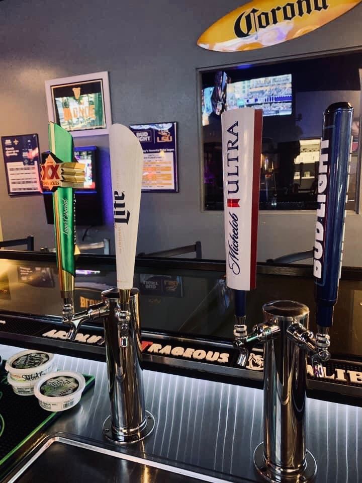 Beer taps at a bar with Corona sign in background, featuring Miller Lite, Michelob Ultra, and Bud Light handles.