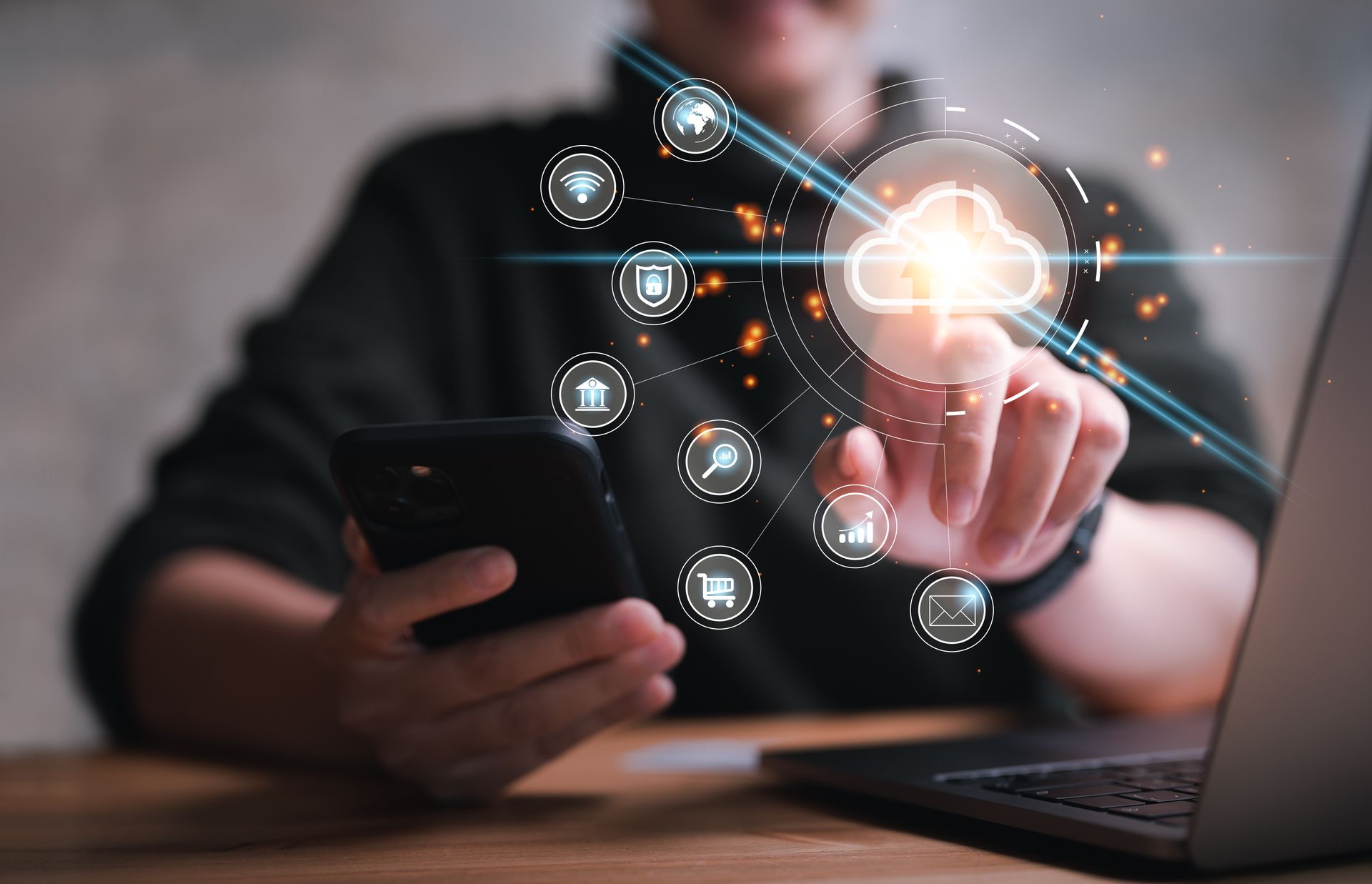 Person using a smartphone taps a glowing digital network icon above a laptop on a desk