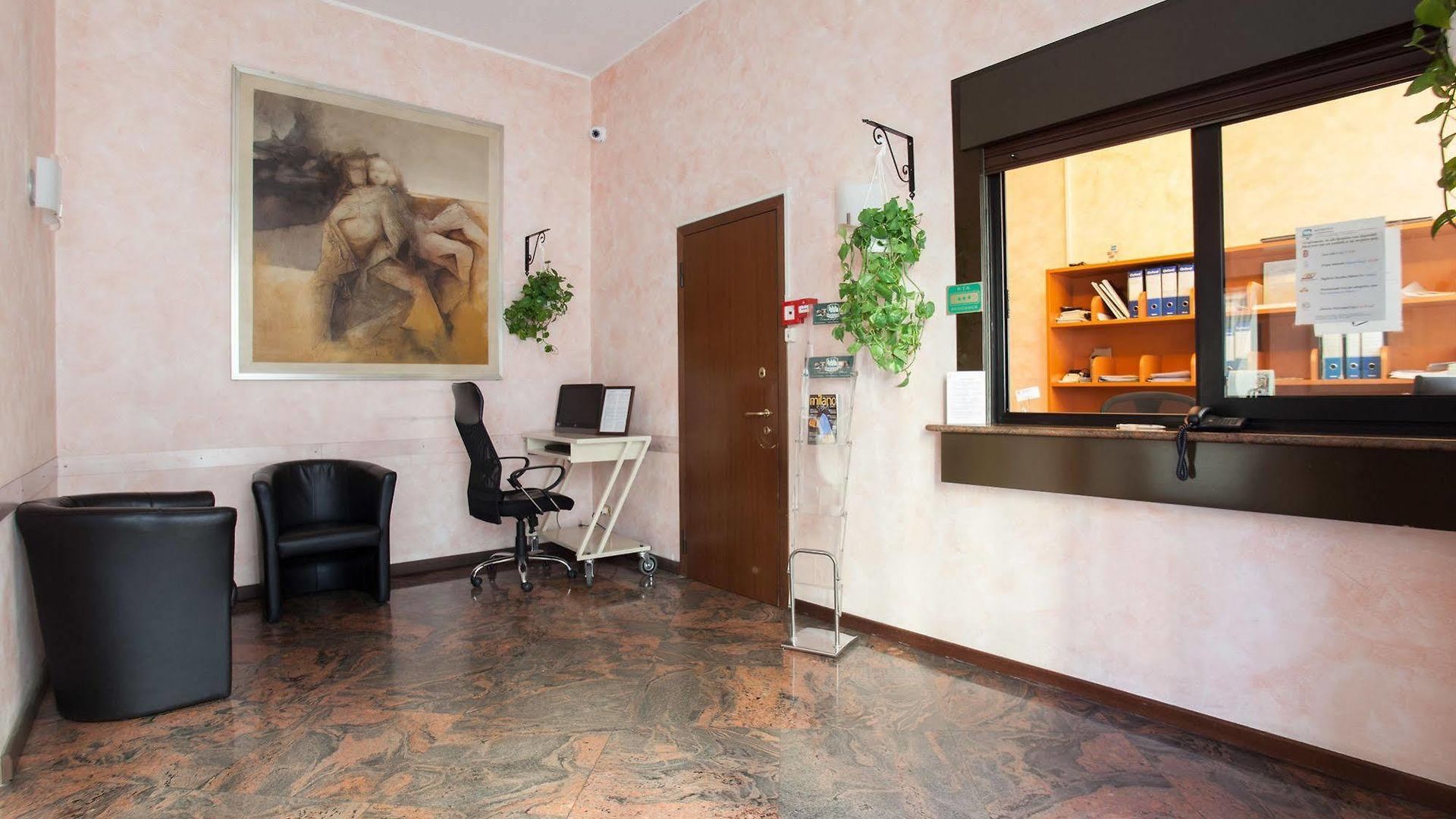 Una stanza con una scrivania, delle sedie e un dipinto sul muro