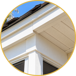 Close-up of white house eaves and corner trim with a gutter against the roofline