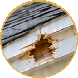 Damaged white siding with a large hole and exposed wood under roof shingles