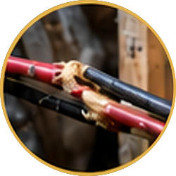 Close-up of two red and black rods tied together with rope on a wooden frame