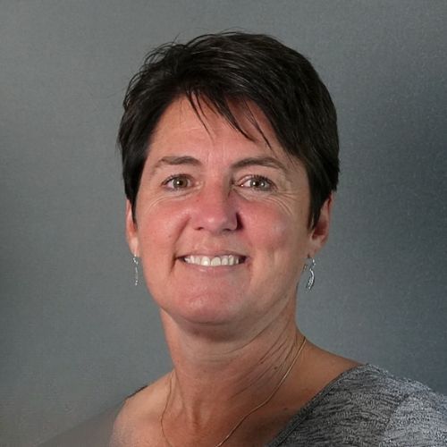 A woman with short hair and earrings is smiling for the camera.