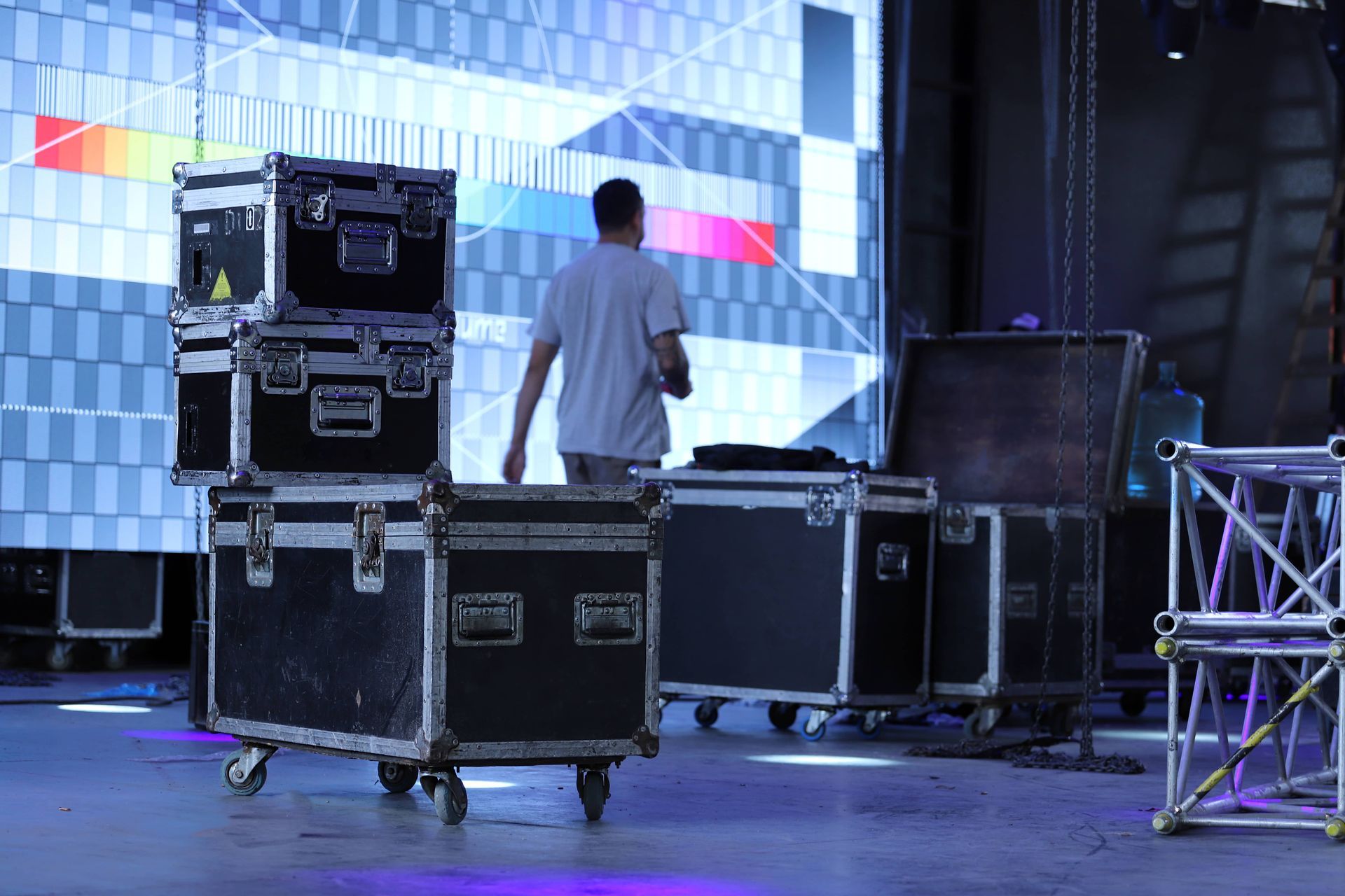 A man is pushing a cart with a bunch of cases on it.
