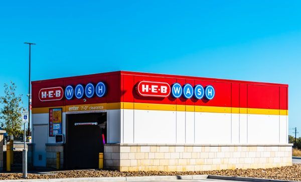 A red , white and yellow car wash with a blue sky in the background.