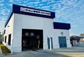 A white building with a blue roof is a car wash.