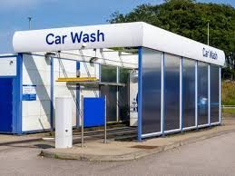 A car wash is located in the middle of a parking lot.