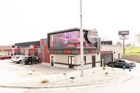 A fast food restaurant with cars parked in front of it.