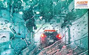 A car is driving through a car wash in the rain.