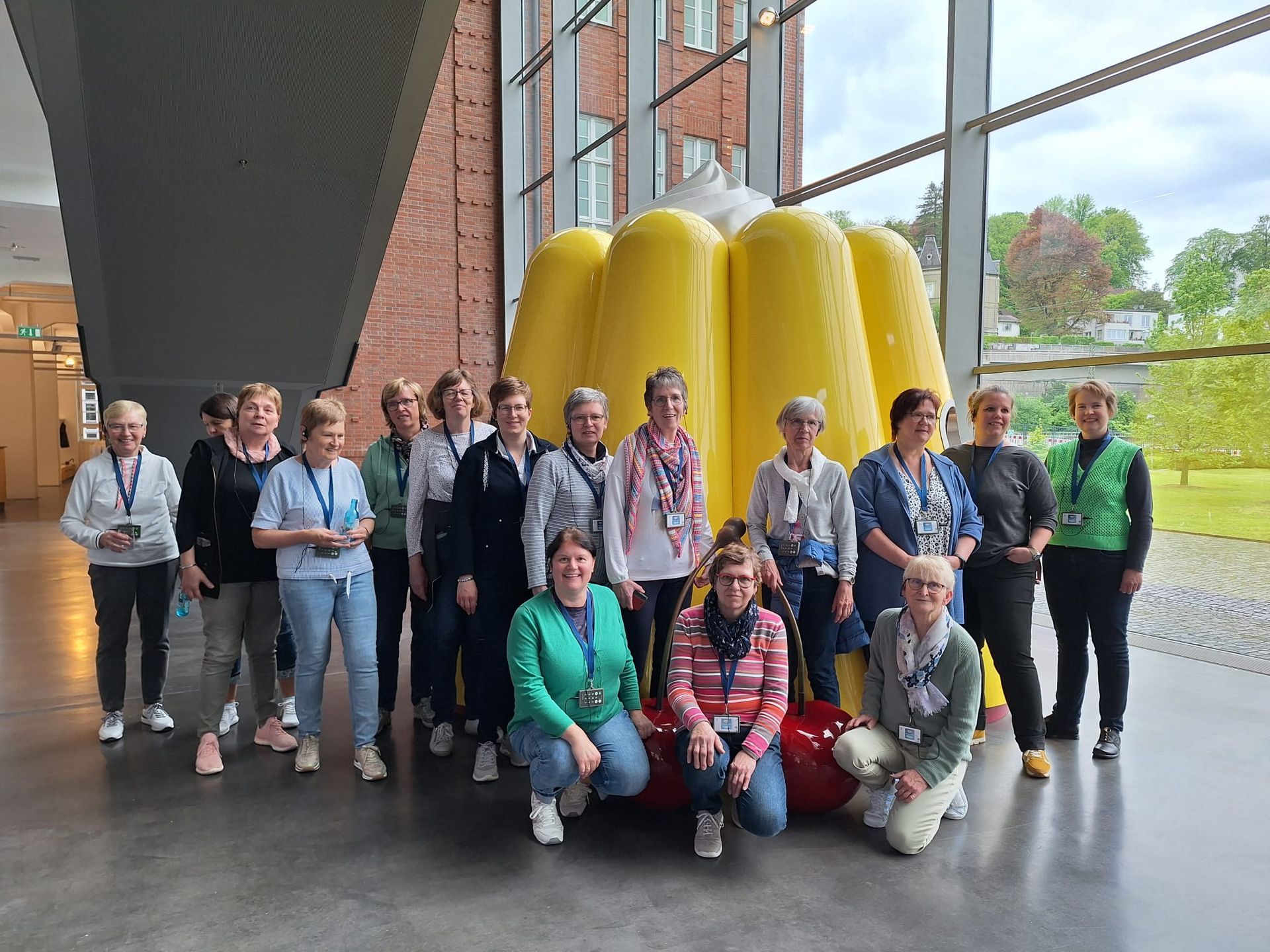 Eine Gruppe von Menschen posiert für ein Foto vor einem großen gelben Objekt.