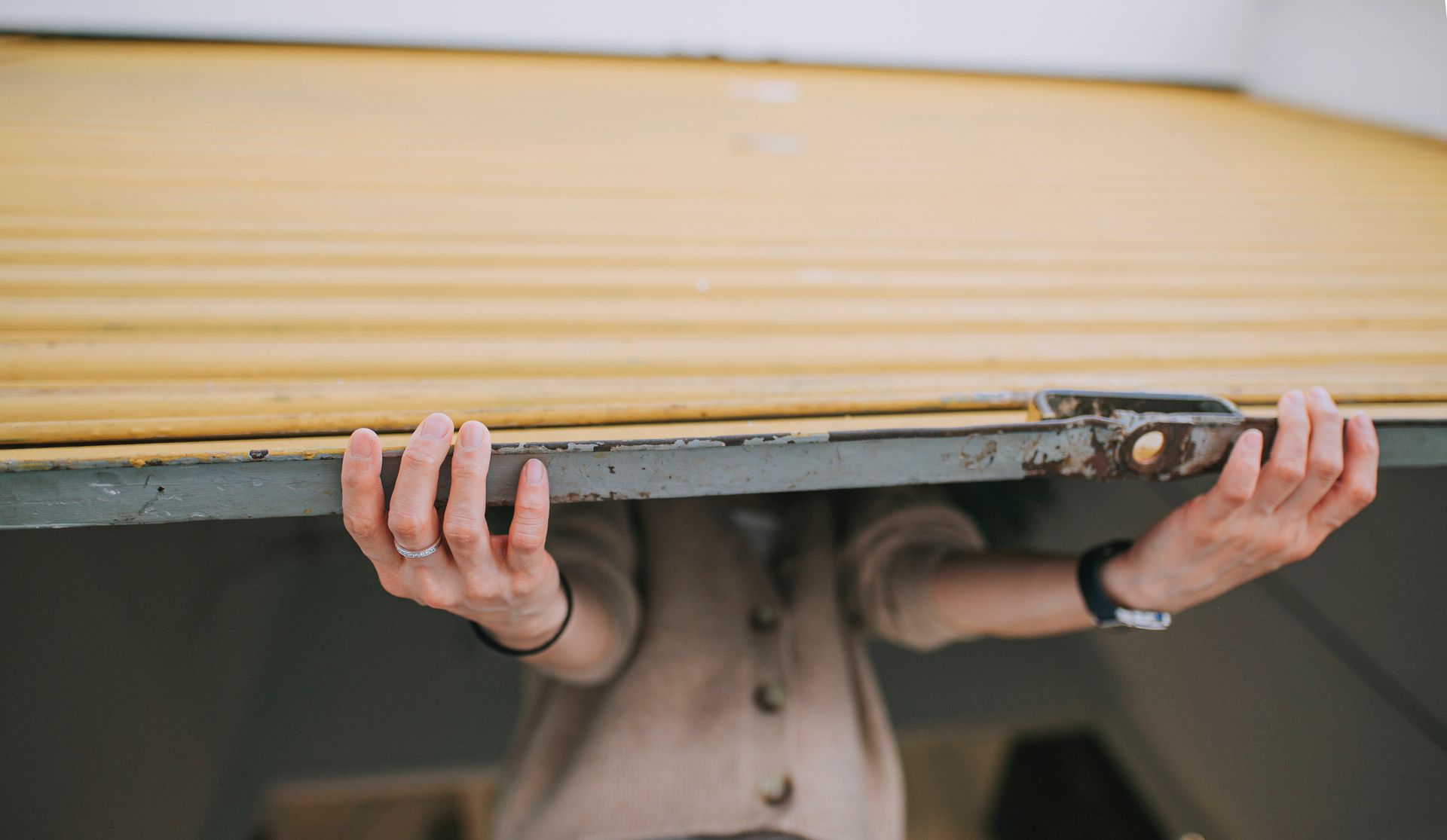 Person lifting a yellow garage door.