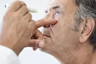 Old man getting his eye check with a pen light