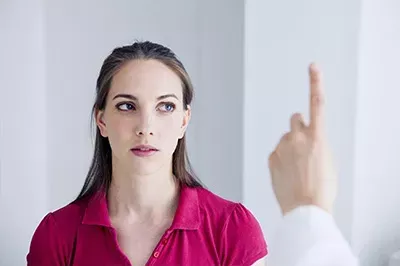 Lady getting an eye exam, doctor raising on finger up