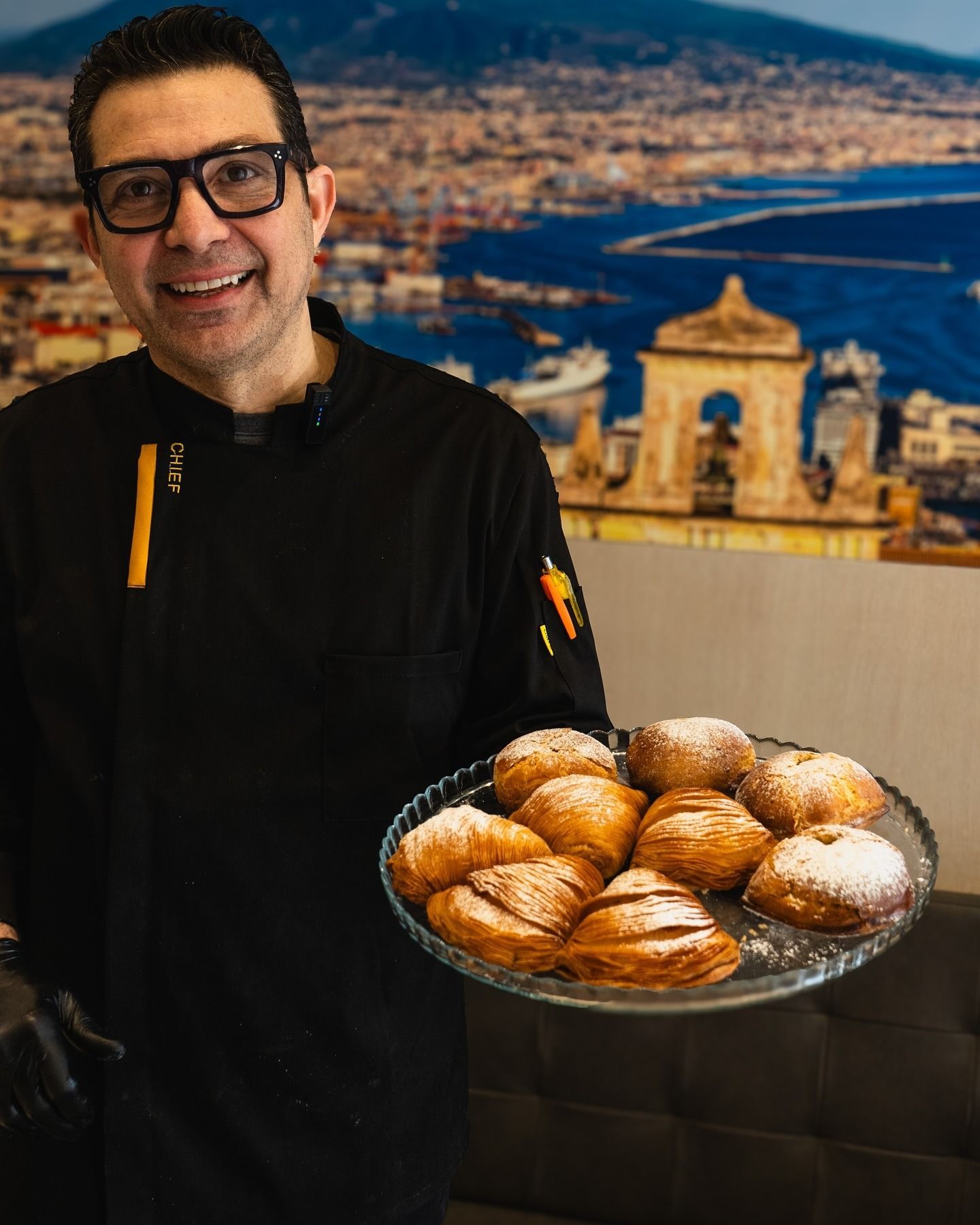 Due pasticcini spolverati di zucchero a velo su un piatto beige. Tavolo di legno, piccola ciotola di granuli bianchi.