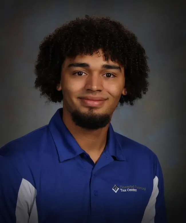 Studio portrait of a person in a blue polo shirt, smiling against a dark background.