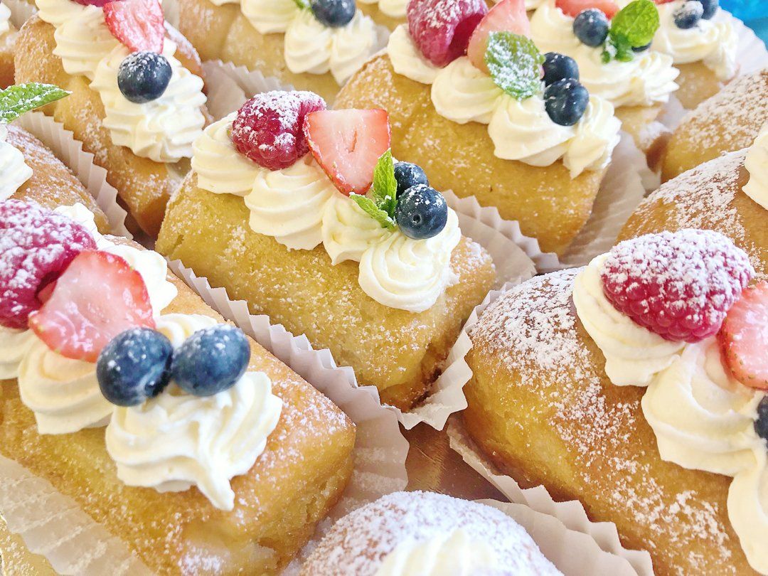 A close up of a tray of desserts with whipped cream and berries.
