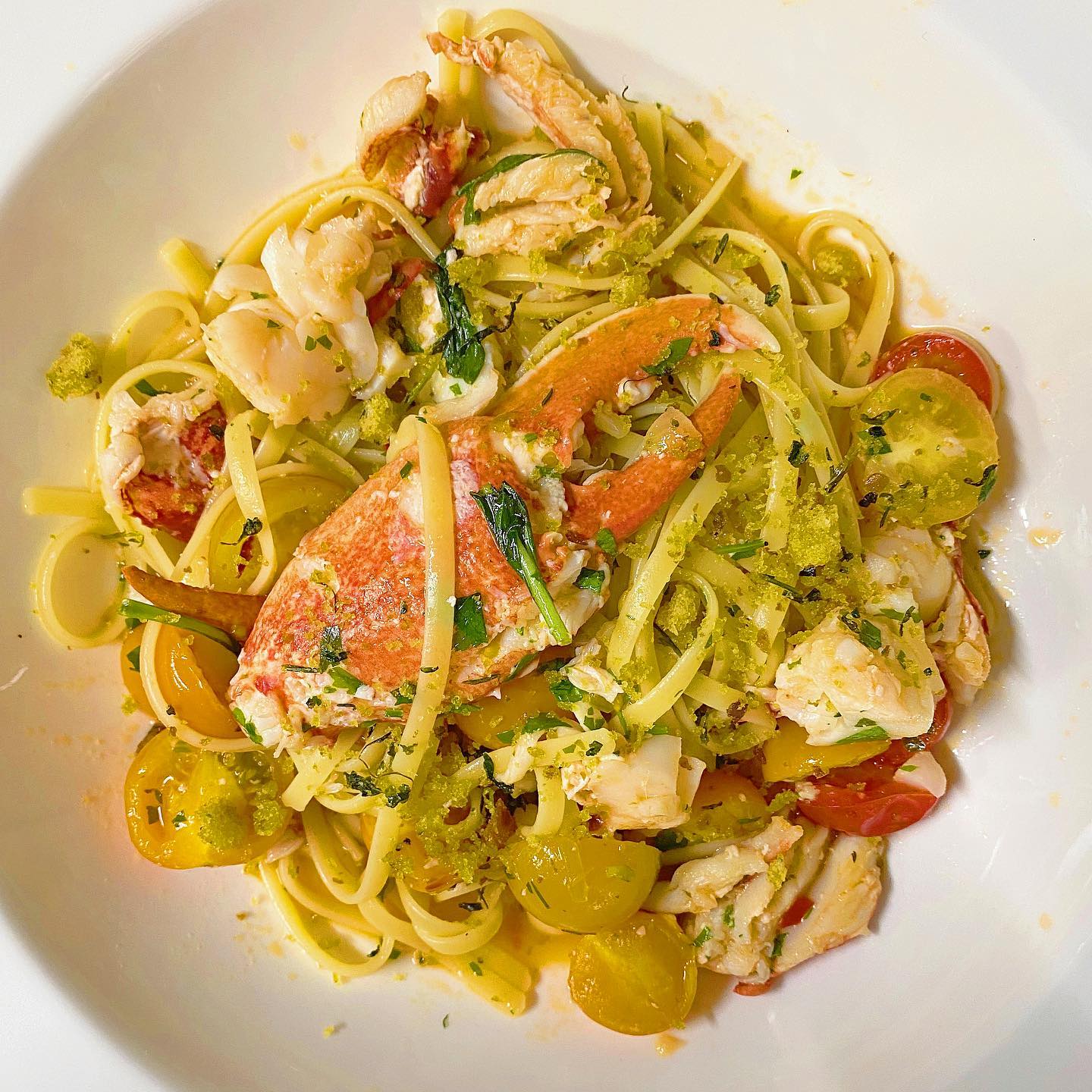 A white bowl filled with pasta , shrimp , and tomatoes.