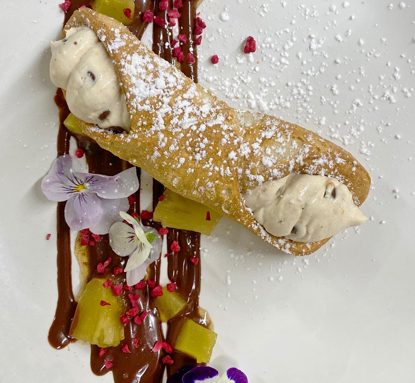 A dessert with powdered sugar and chocolate sauce on a white plate