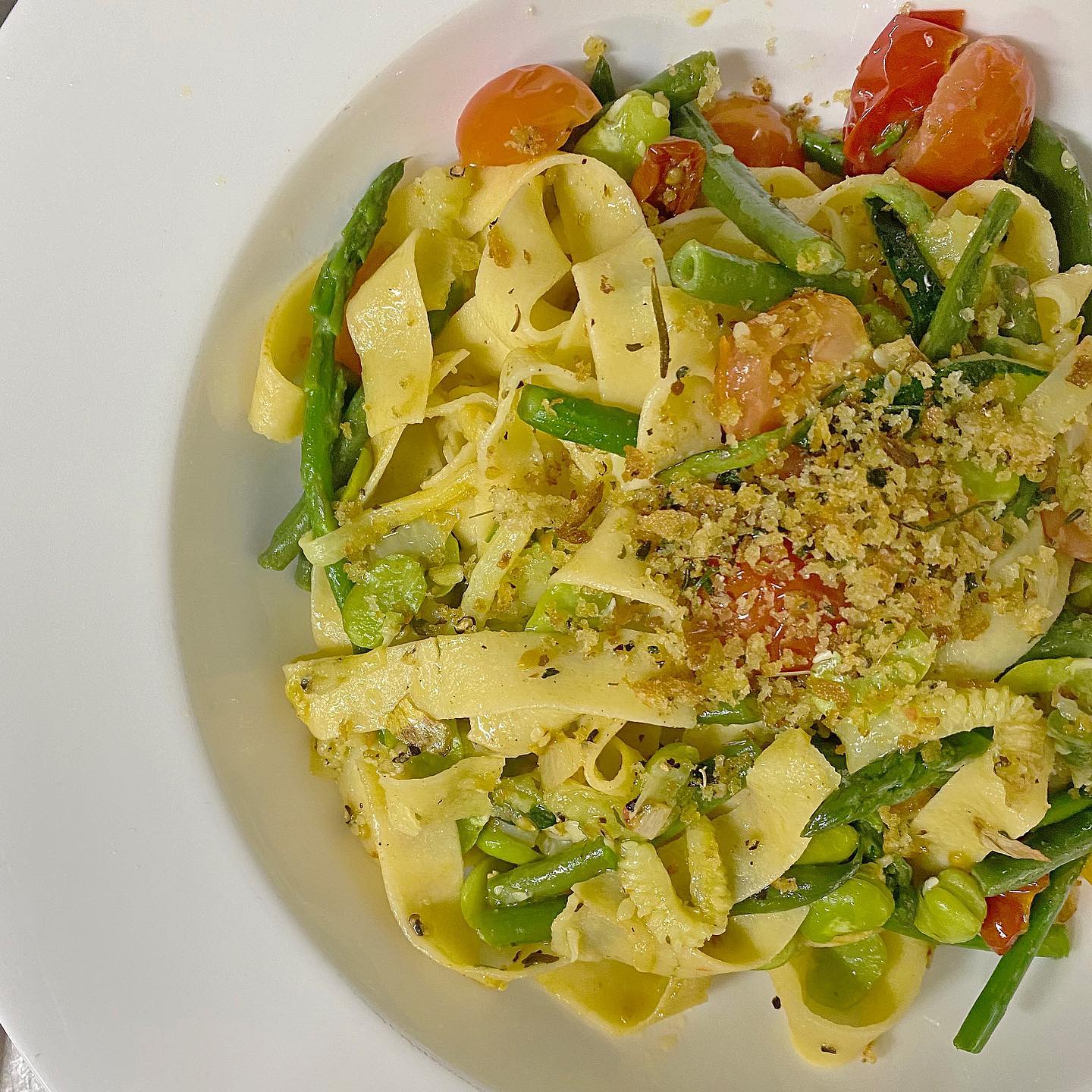 A white plate topped with pasta asparagus and tomatoes