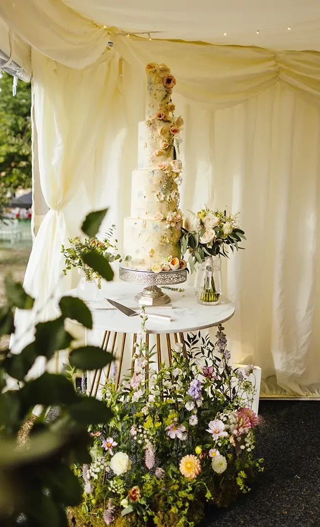 A wedding cake is sitting on top of a table surrounded by flowers.