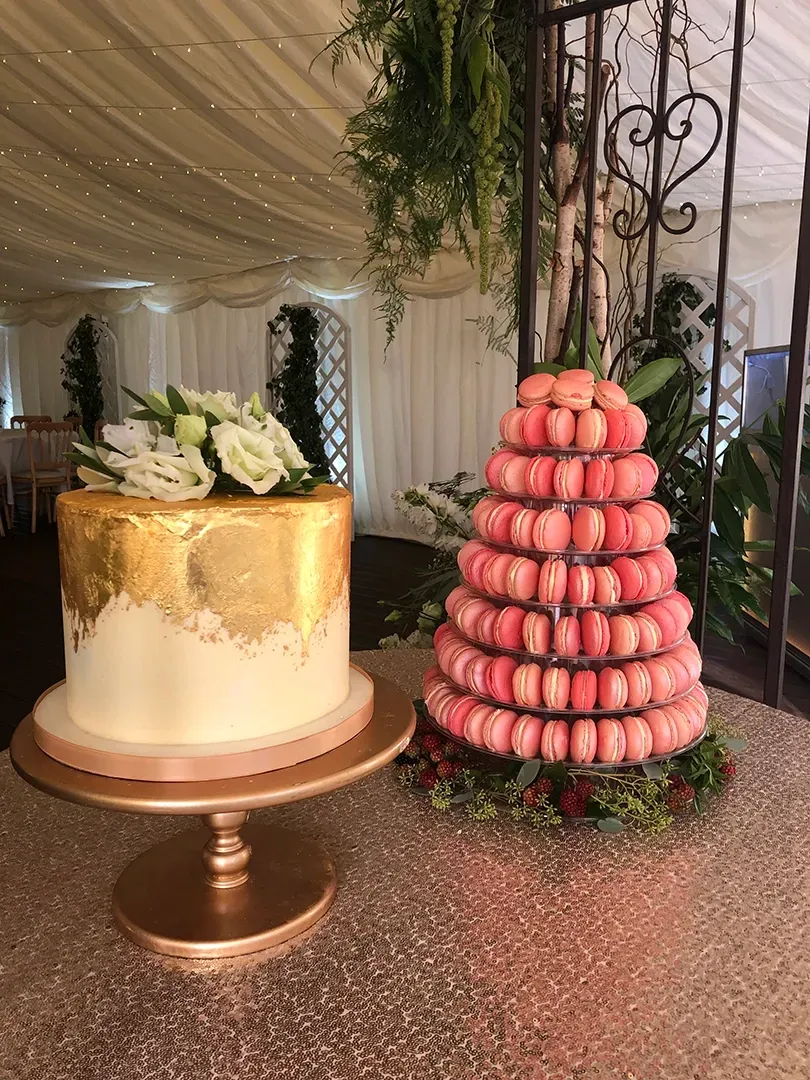 A wedding cake and a macaroon tower are on a table.