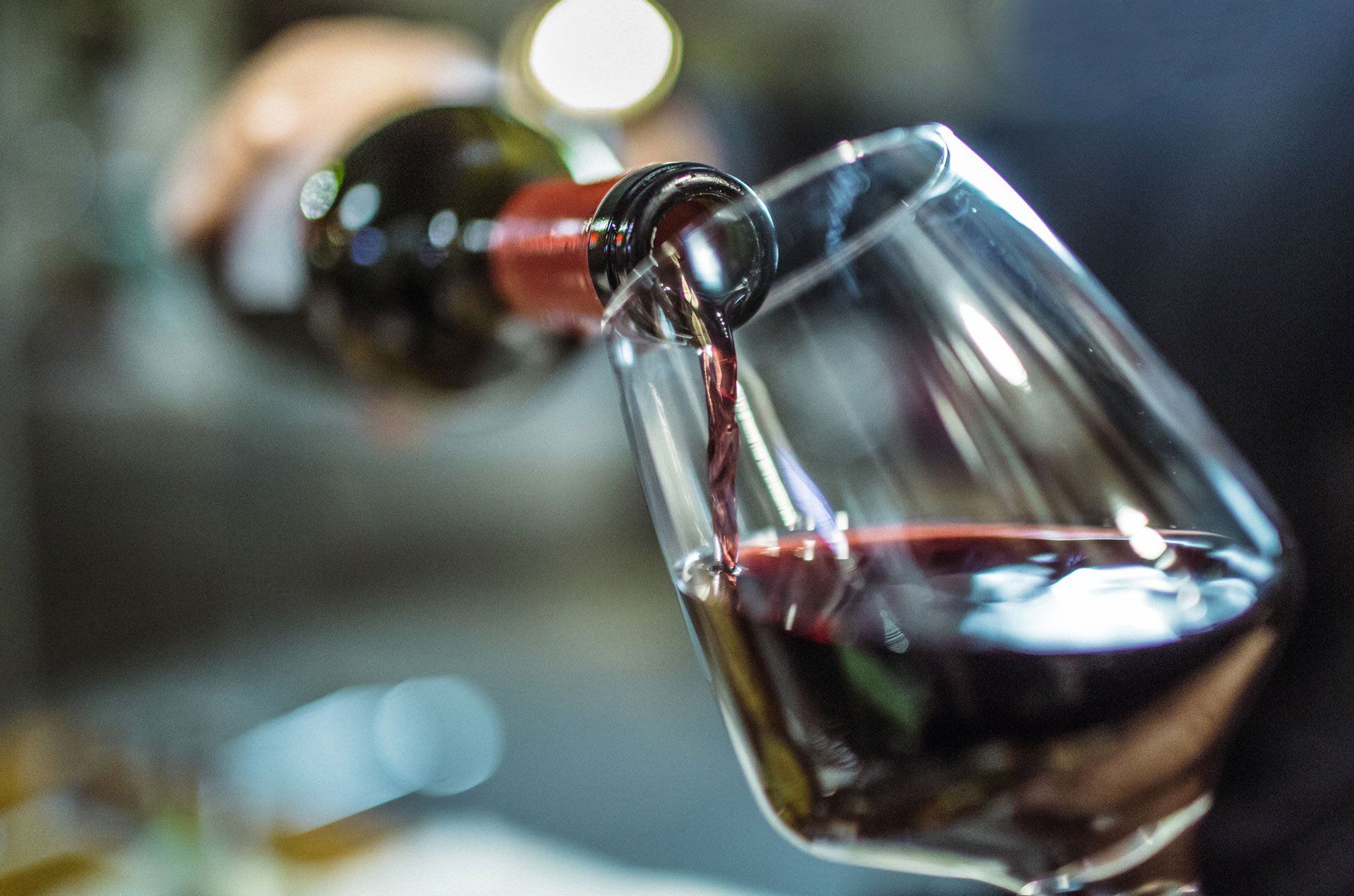 A person is pouring red wine into a glass.