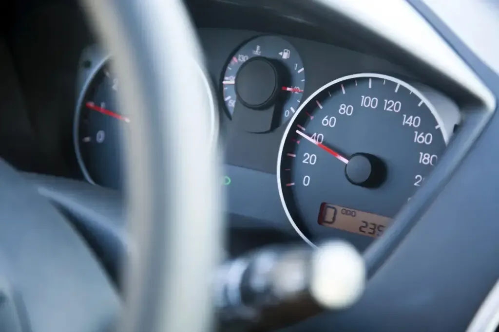 A car dashboard showing a speedometer needle pointing to approximately 40 km/h, with a steering wheel in the foreground.