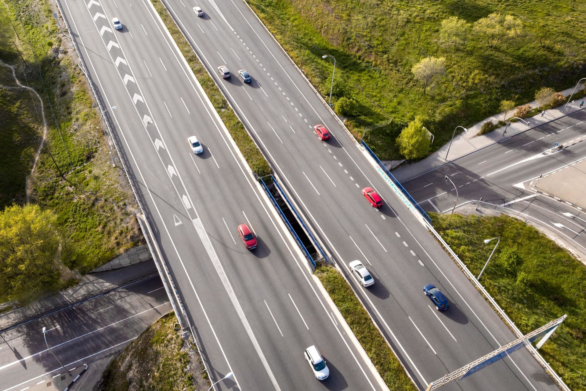 Aerial view of cars driving on a multi-lane highway through green countryside.
