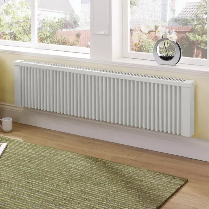 White baseboard heater under a window with a green rug in a room.