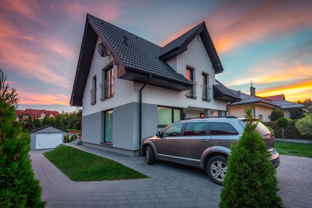 Modern house with a parked SUV in the driveway at sunset