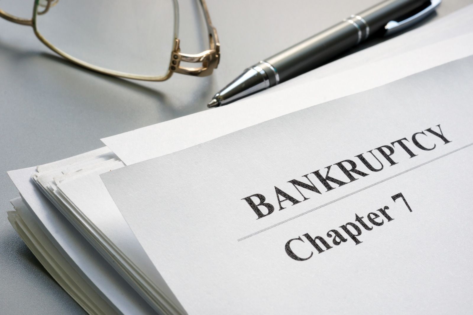 Bankruptcy Chapter 7 document with glasses and pen on a desk