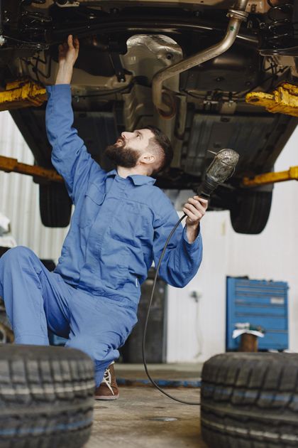 Auto Mechanic Inspecting Vehicle Undercarriage | Knost Tire & Automotive