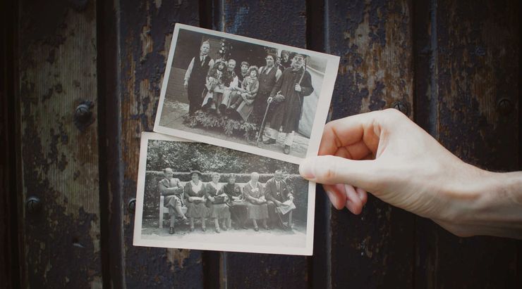 Hand holding two black-and-white vintage photos over a dark wooden surface