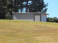 Small white utility building on a grassy hill under a clear blue sky
