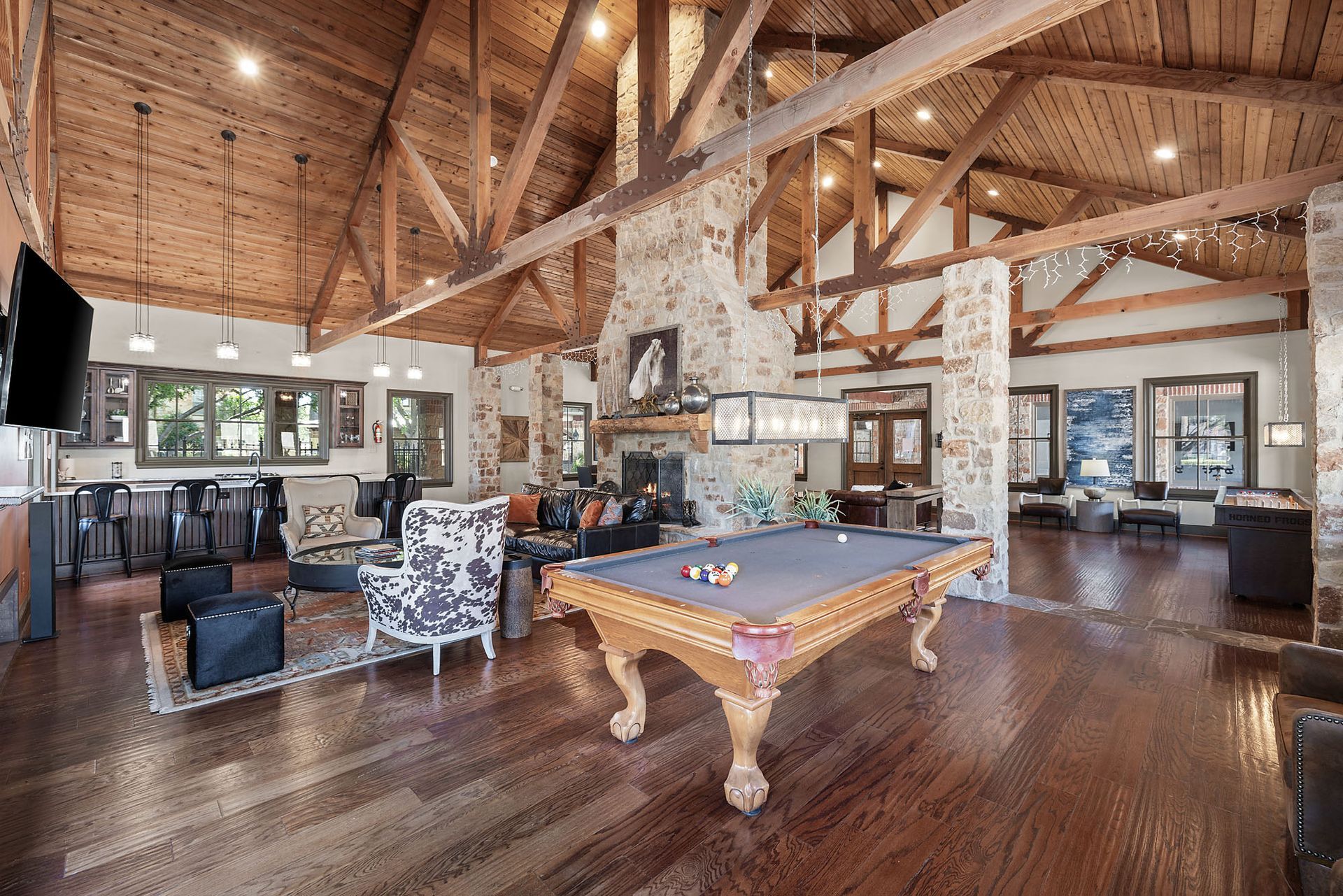 Rustic lodge game room with vaulted wood ceilings, billiard table, and large windows at Marquis at Bellaire Ranch in Fort Worth, TX