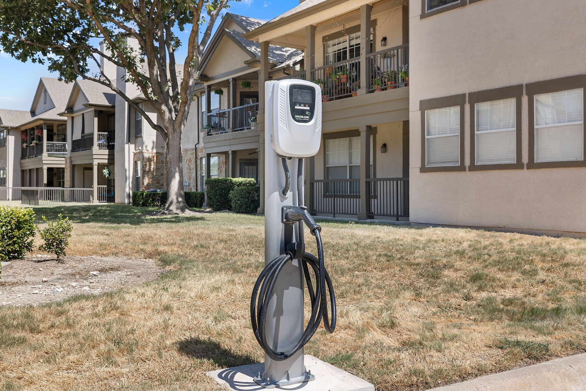 Electric vehicle charging station on a concrete pad outside apartment buildings at Marquis at Bellaire Ranch in Fort Worth, TX.