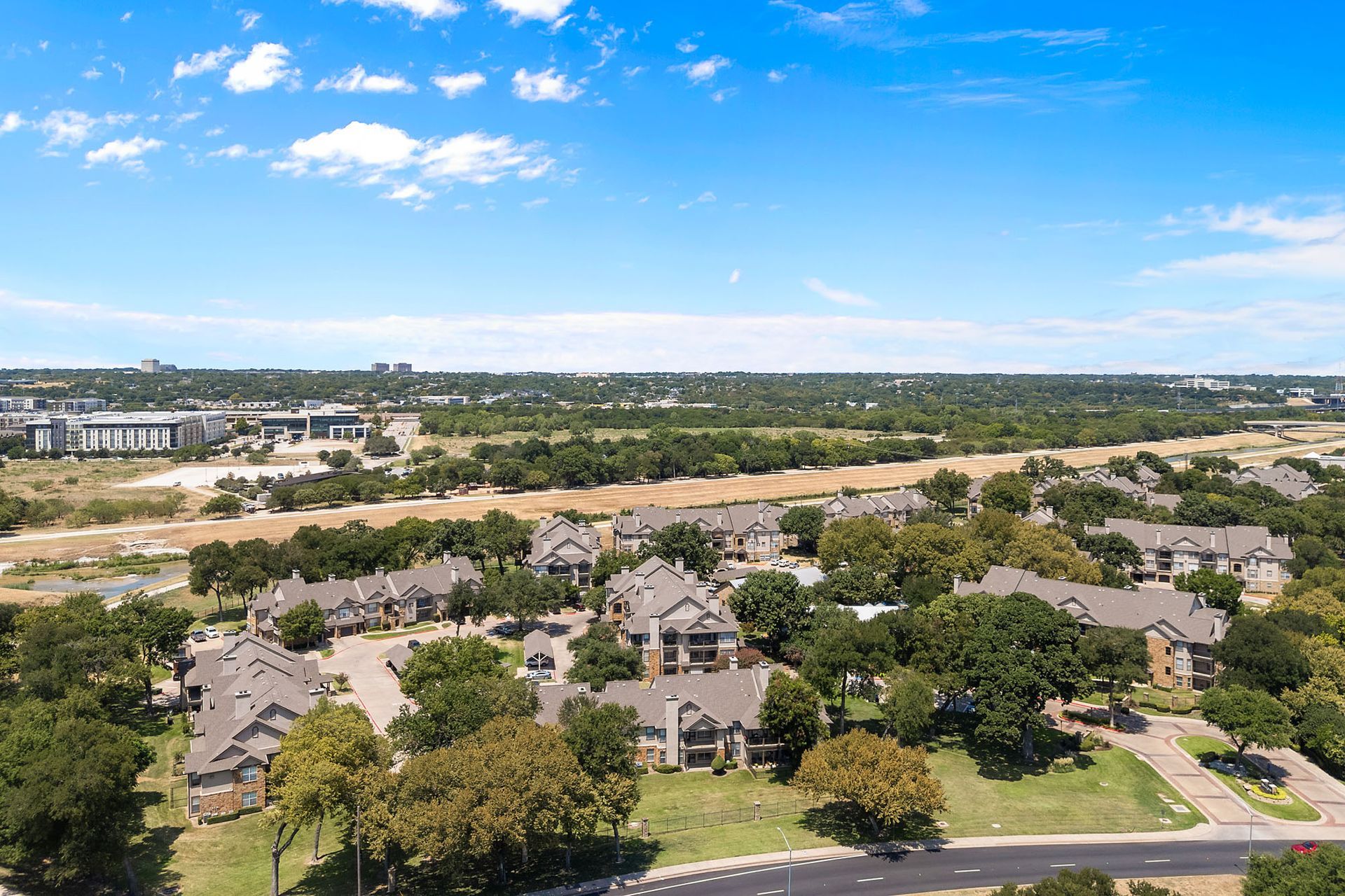Aerial view of a suburban neighborhood with trees, roads, and a blue sky at Marquis at Bellaire Ranch in Fort Worth, TX