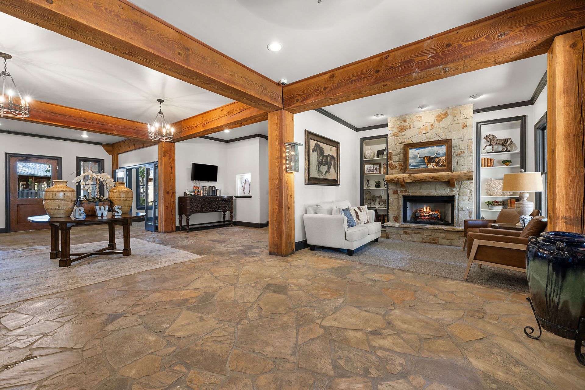 Spacious rustic living room with exposed wood beams, stone fireplace, and leather seating at Marquis at Bellaire Ranch in Fort Worth, TX