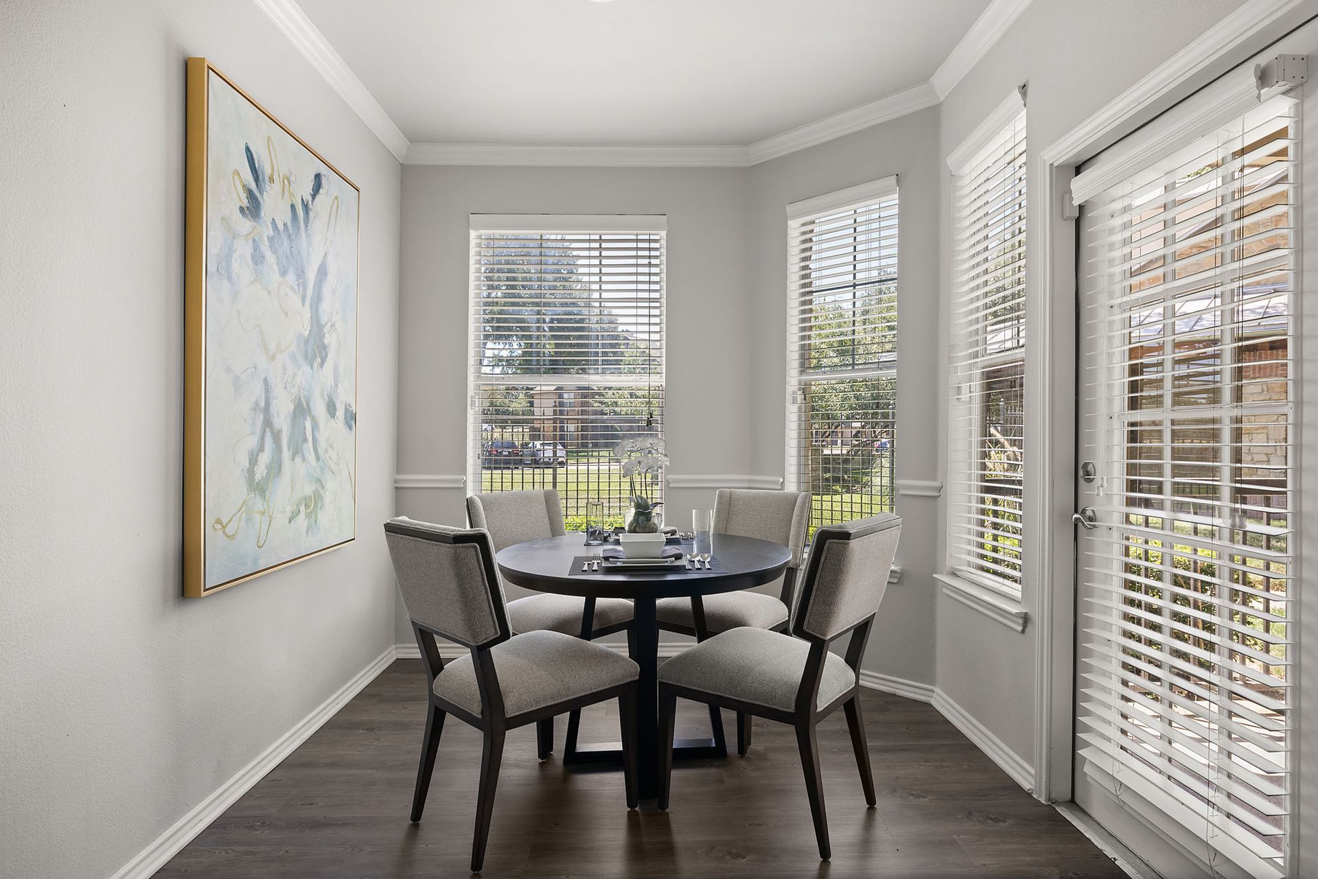 Bright dining nook with round table, four gray chairs, large windows, and a framed wall painting at Marquis at Bellaire Ranch in Fort Worth, TX