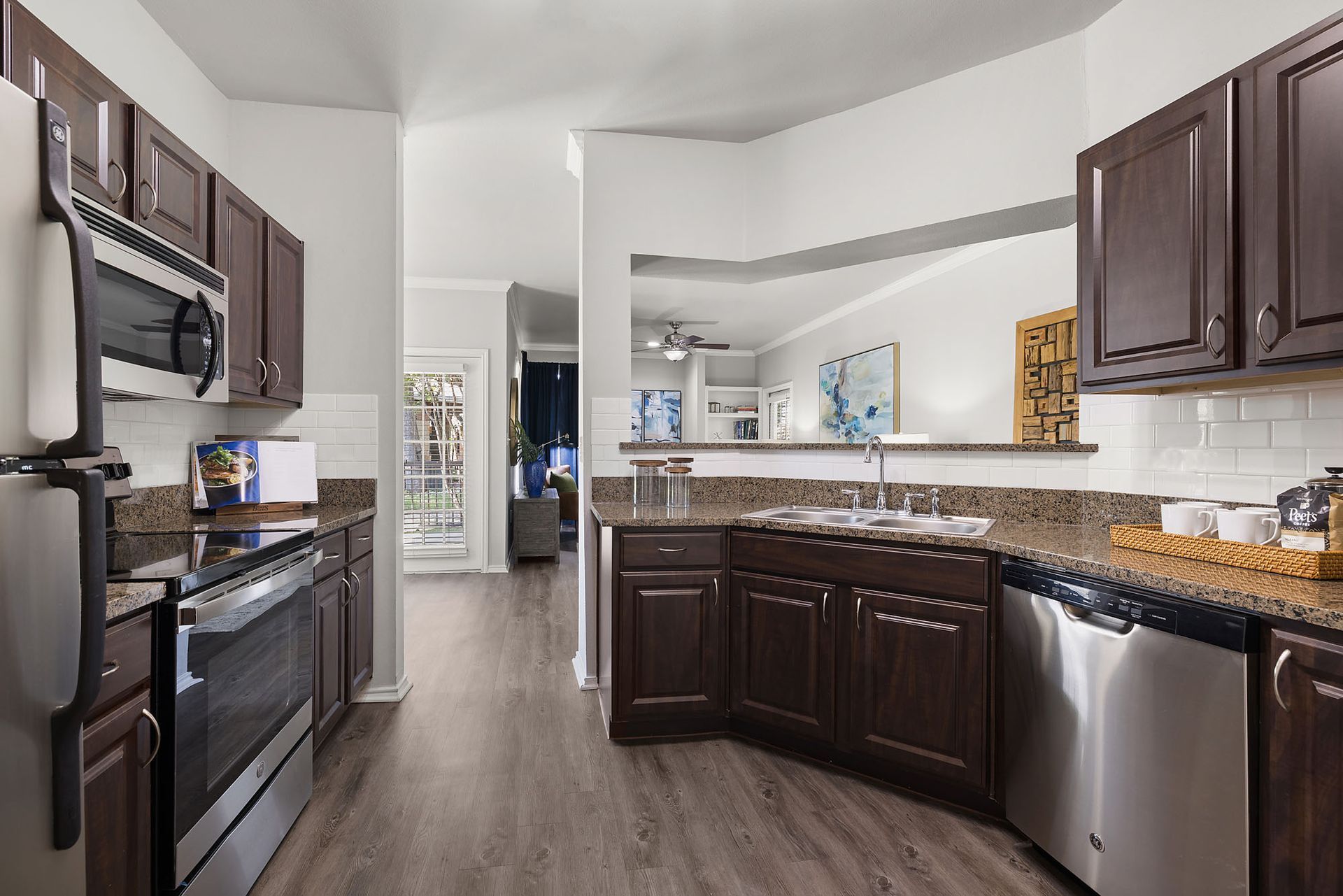 Modern kitchen with dark cabinets, stainless appliances, and a curved breakfast bar at Marquis at Bellaire Ranch in Fort Worth, TX.
