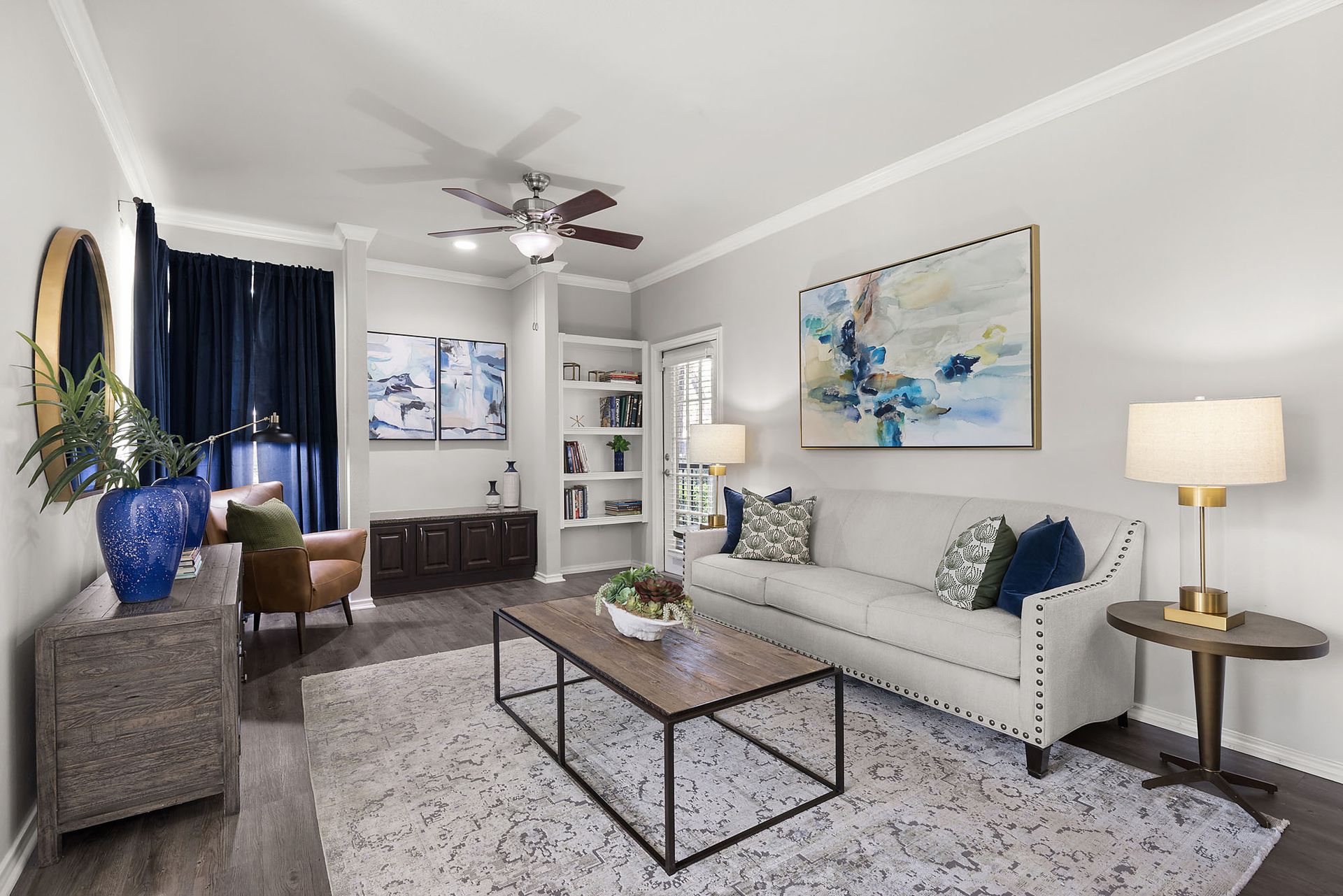 Bright living room with gray sofa, coffee table, armchair, plants, and blue accents at Marquis at Bellaire Ranch in Fort Worth, TX