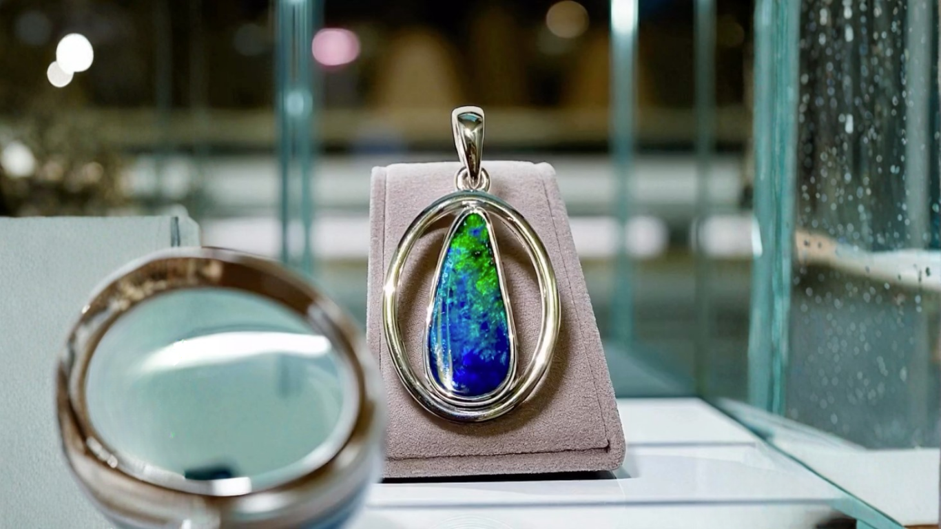 Hands Holding a Ring With a Large Stone, Near a Jewelry Display — Regency Jewellers in Cairns City, QLD