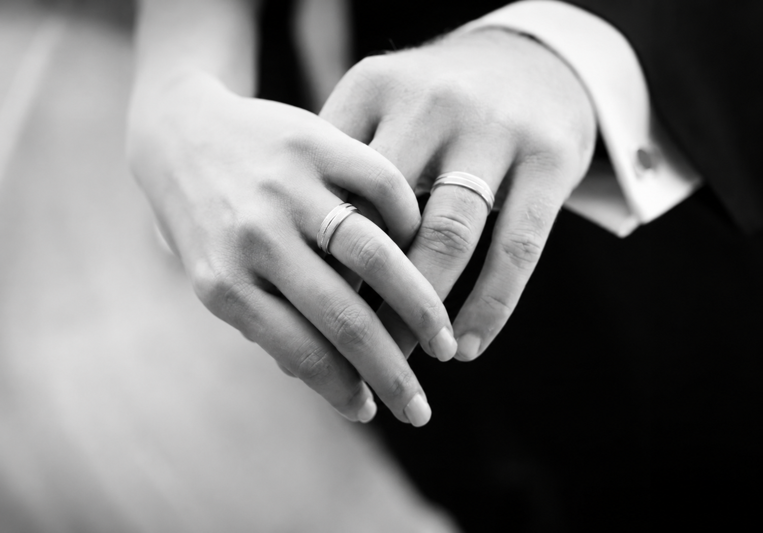 Black-and-white Close-up of Two Hands With Wedding Rings Gently Clasped Together — Regency Jewellers in Cairns City, QLD