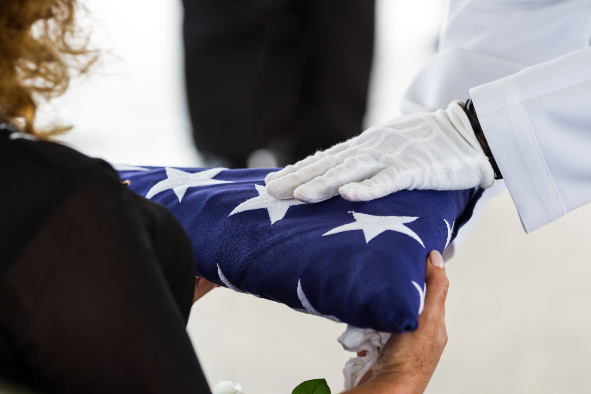 Gloved hands folding a folded American flag during a solemn ceremony
