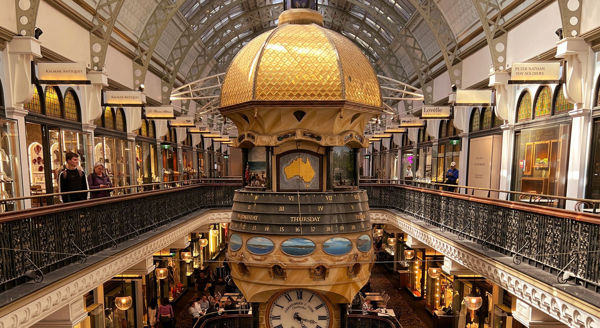 Grand ornate indoor atrium with gold dome, balconies, and decorative arches bustling with shoppers